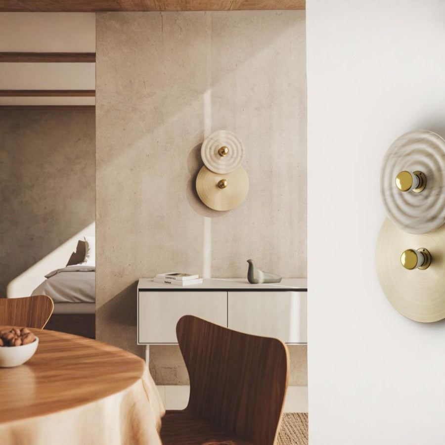 2 rounds discs wall light in marble and metal finish in a dining room