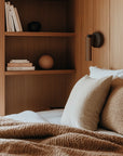 A warm theme bedroom with books, objects and bed side wall light in leather and black metal. 