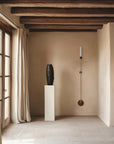 A nordic theme beige room with a sculpture on a plinth and a long wall light