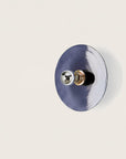A blue colour wall light in shape of a disc on a light cream colour background