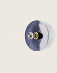 A blue colour wall light in shape of a disc on a light cream colour background