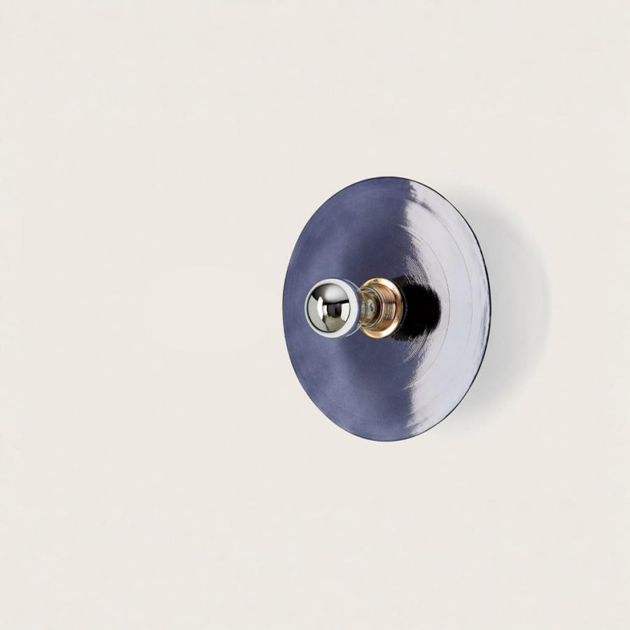 A blue colour wall light in shape of a disc on a light cream colour background