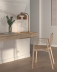 A minimal study table with wooden chair, art objects and a table lamp in bronze finish