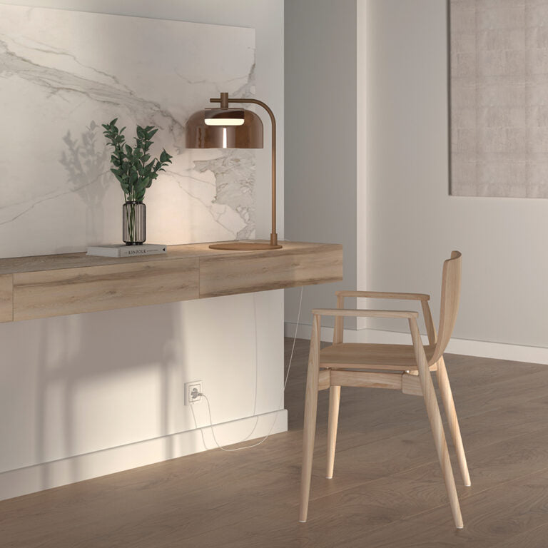 A minimal study table with wooden chair, art objects and a table lamp in bronze finish