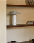 A table lamp in white marble and brass shade styled on a shelf in a modern interiors