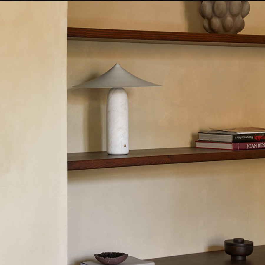 A table lamp in white marble and brass shade styled on a shelf in a modern interiors