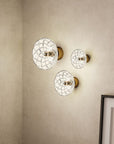A set of three crystal wall lamps in a warm corner of a living room styled with decorative elements. 