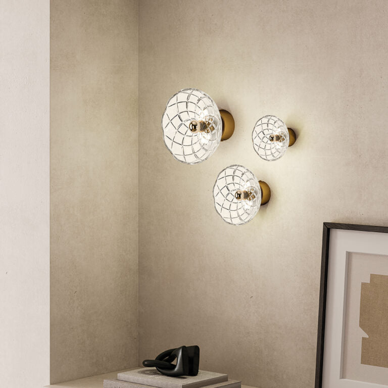 A set of three crystal wall lamps in a warm corner of a living room styled with decorative elements. 
