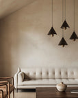 4 modern pendant lamps in black colour  suspending from ceiling above a modern design sofa in a Japandi style interiors