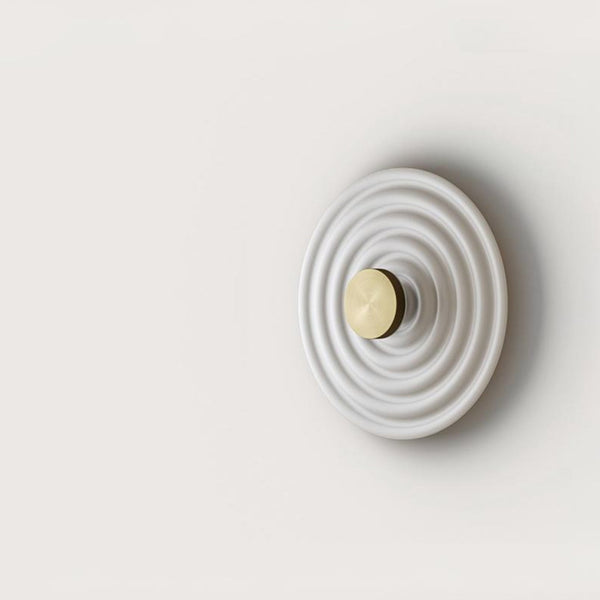 A round disc wall light on a light grey back ground. 