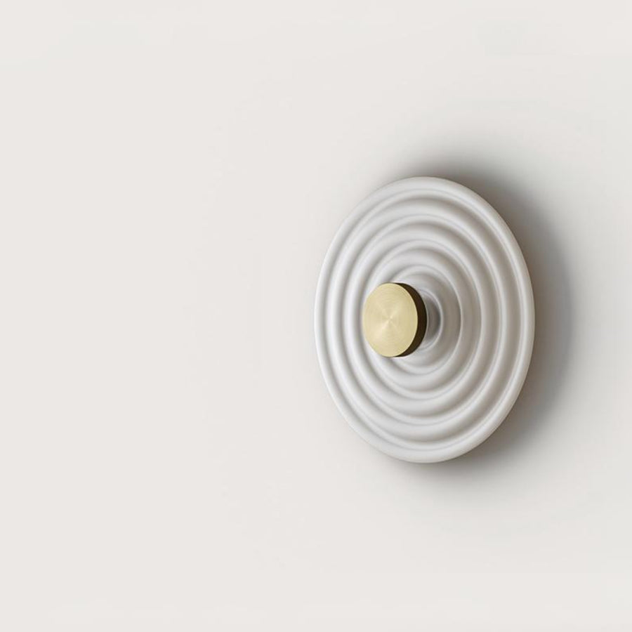A round disc wall light on a light grey back ground. 