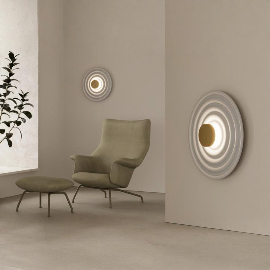 A living room corner with a round disc wall lights and green plant. 