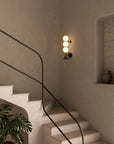 A warm beige interior showing spiral staircase and a modern design wall sconce with artefacts in a niche. 