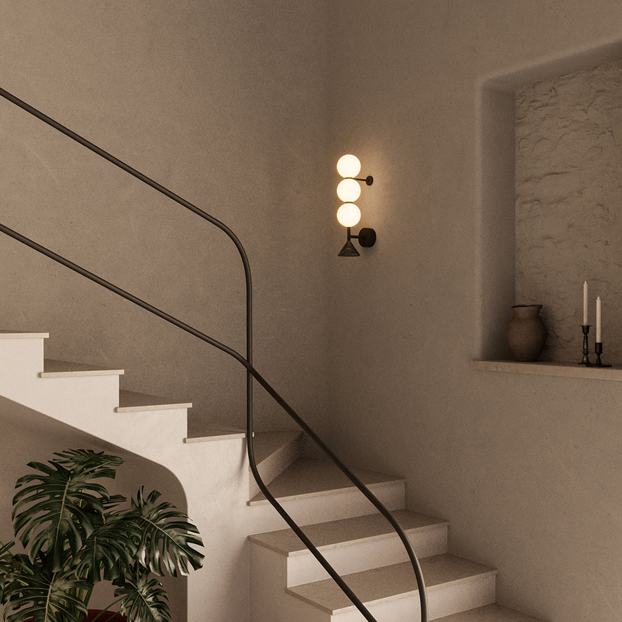 A warm beige interior showing spiral staircase and a modern design wall sconce with artefacts in a niche. 