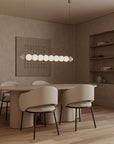 A Japandi theme dining room with artefacts, dining table, chairs, wall art and suspended light. 