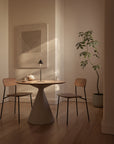 Dining area with a round table and two chairs in a softly lit room.