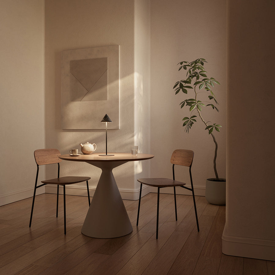 Dining area with a round table and two chairs in a softly lit room.