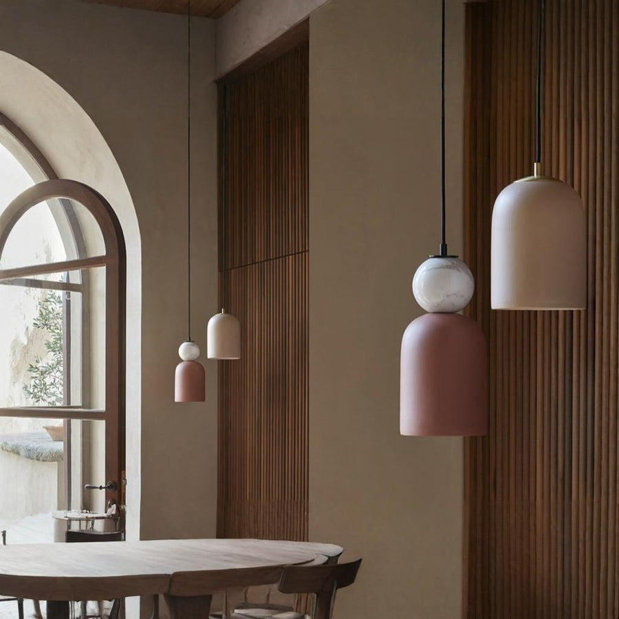 A pair of colourful pendant lights hanging from the ceiling in marble and ceramic in a warm theme interiors. 