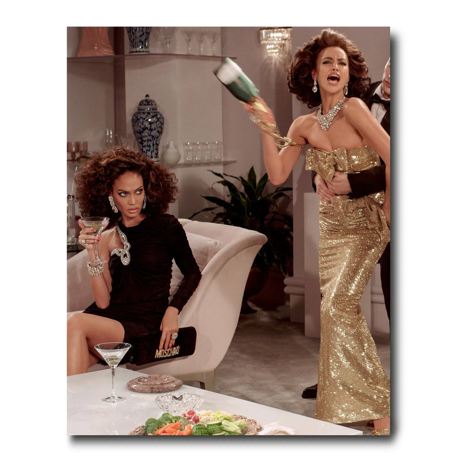 A woman in a glamorous gold dress is holding a glass of champagne, exuding luxury and style in the world of Assouline Coffee Table Book Moschino.