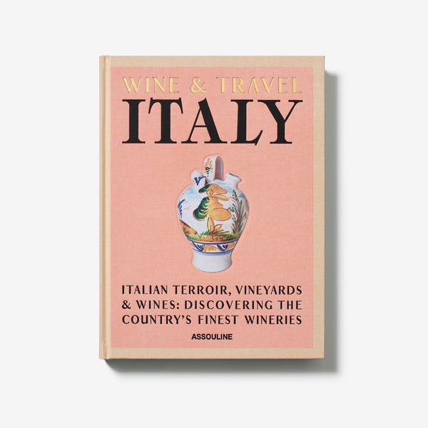 On a white background. A luxurious hardbound Assouline coffee table book, Wine & Travel Italy, featuring Italy's top vineyards, fine wines, and the art of winemaking.