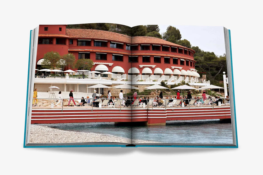 A seaside resort with red facade with waterfront terrace double spread in a luxurious Assouline's Monte Carlo coffee table book, featuring a vibrant cover with images of Monaco's iconic landmarks, available at Spacio India.