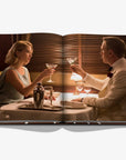 Open book showing a scene of a man and woman at a dinner table with drinks.