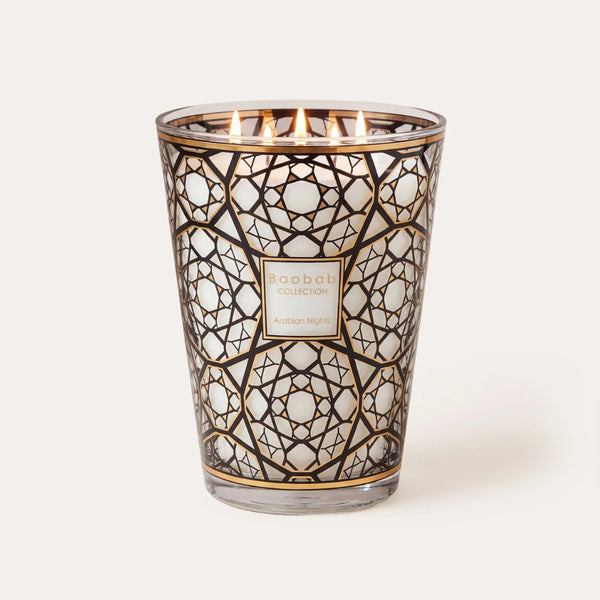A lit scented candle in a clear glass vessel with an intricate black and gold geometric filigree pattern. The candle has six visible flames at the top and a central square label that reads 'MAHABBA COLLECTION' and 'MAGNIFICENT NIGHT'.