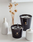 Baobab Encre De Chine candles Max 16 MAX16ENC on a table next to a vase, emanating fragrance.