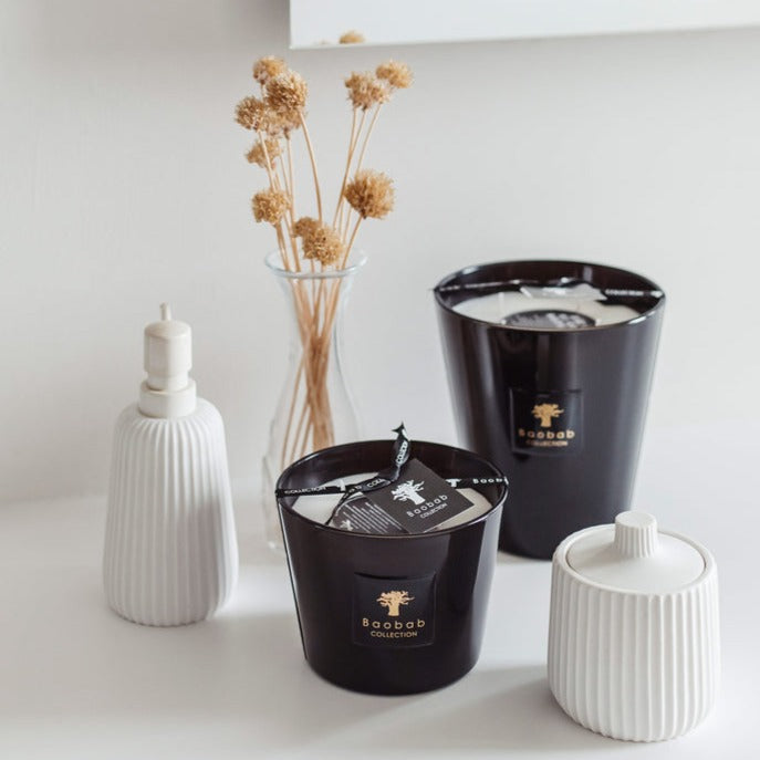 Baobab Encre De Chine candles Max 16 MAX16ENC on a table next to a vase, emanating fragrance.