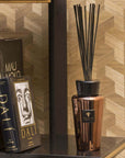 Baobab Cyprium Diffuser 500ml positioned on a bookshelf next to premium art books, enhancing interiors with its warm metallic elegance; available from Baobab Collection at Spacio India.