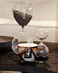Baobab Stones Marble Candle styled with hourglasses on a dark tabletop – luxury fragrance decor from Spacio India