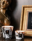 Set of two Baobab Stones Marble Candles lit beside bronze sculpture and gold frame, styled exclusively at Spacio