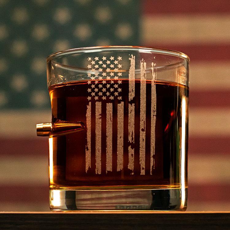 Glass with American flag design filled with a dark liquid, American flag in the background