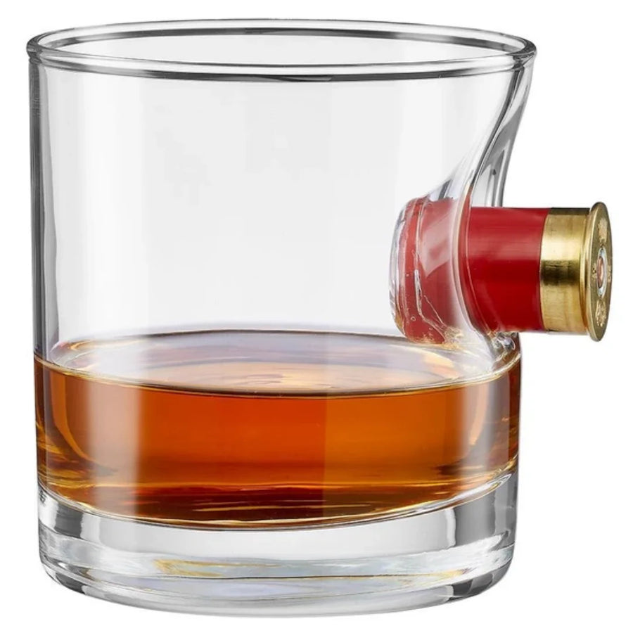 Glass filled with whiskey in a glass with shotgun shell casing, on a white background