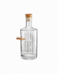 Clear whiskey decanter with a wooden cap and real bullet on a white background from the American brand Benshot available at Spacio retail stores in Mumbai & Kolkata. 