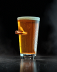 Pint Glass of beer with a bullet on a black background
