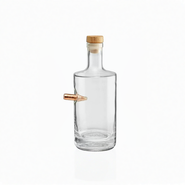 Clear whiskey decanter with a wooden cap and a copper bullet on a white background from American brand Benshot  available at Spacio retail stores in Mumbai & Kolkata. 