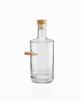 Clear whiskey decanter with a wooden cap and a copper bullet on a white background from American brand Benshot  available at Spacio retail stores in Mumbai & Kolkata. 