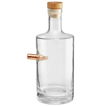 Clear whiskey decanter with a wooden cap and a copper bullet on a white background from American brand Benshot  available at Spacio retail stores in Mumbai & Kolkata. 