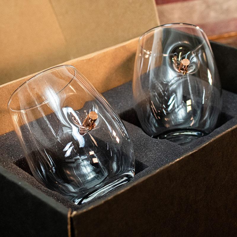 Two clear wine glass with bullets shot in the glass in a cardboard box with foam padding.