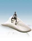 A Butzon Bercker Sculpture Intuition of a man sitting on top of a white sand dune.
