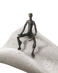 A Butzon Bercker Sculpture Intuition statue of a man sitting on top of a sand dune, portraying both business and motivational vibes.