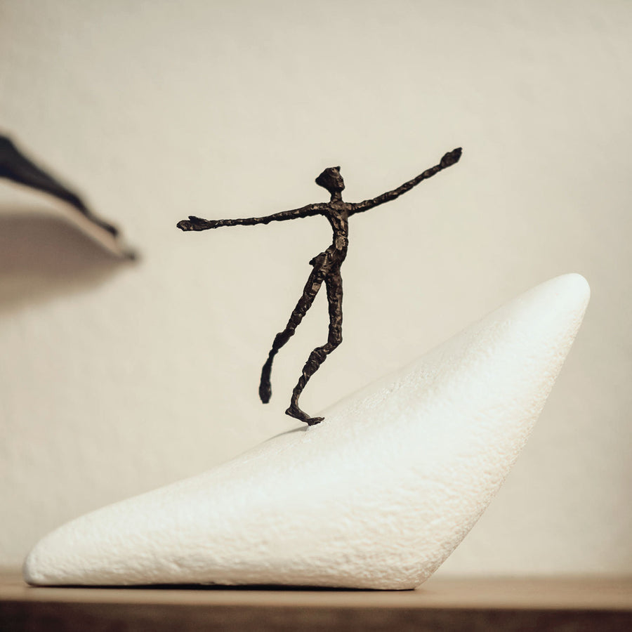 A Butzon Bercker sculpture featuring a man gracefully perched atop a rock named "On The Way To New Horizons".