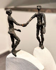 A Butzon Bercker sculpture featuring two people shaking hands on top of a pedestal.