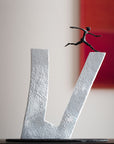 An Butzon & Bercker sculpture, "Who does not Dare," depicting a brave man gracefully leaping over the letter "V".