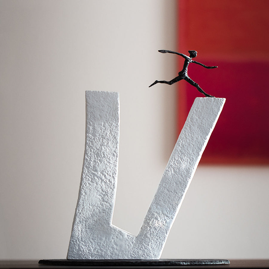 An Butzon & Bercker sculpture, "Who does not Dare," depicting a brave man gracefully leaping over the letter "V".