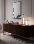 Modern interior with a dark wood sideboard, lamp, and abstract art on the wall.