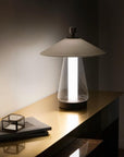 Modern table lamp with a glass base and fabric shade on a wooden surface.
