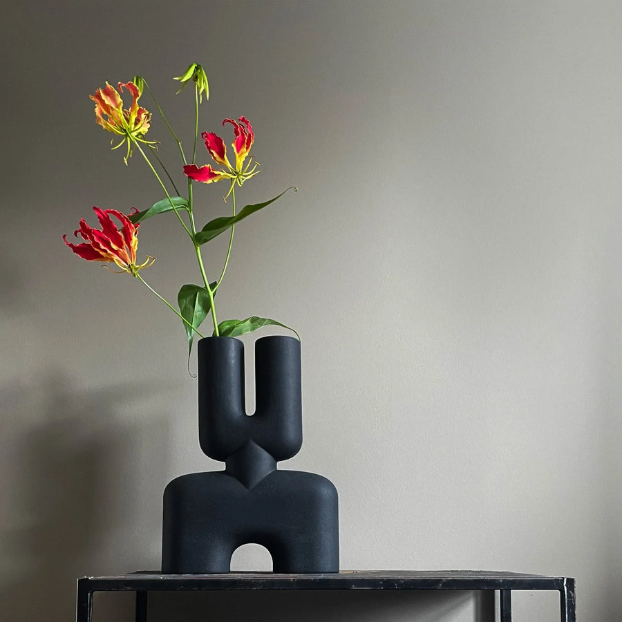 A 101Cph Cobra Double Medio Black 212006 vase with flowers sitting on a table.