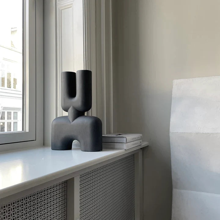 A black 101Cph Cobra Double Medio Black 212006 vase sits on top of a window sill.